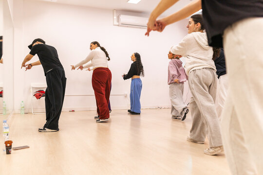 Male instructor teaching urban dance to teenagers in studio
