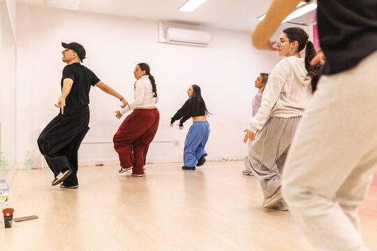 Male instructor teaching urban dance to teenagers in studio