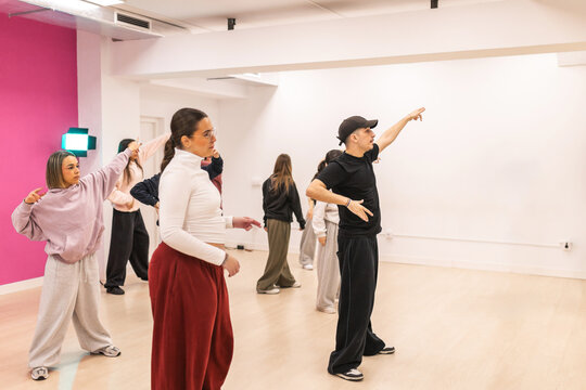 Male instructor teaching urban dance to teenagers in studio