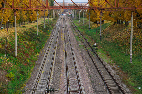Aerial view of railway tracks in autumn outskirts with yellow trees and industrial elements