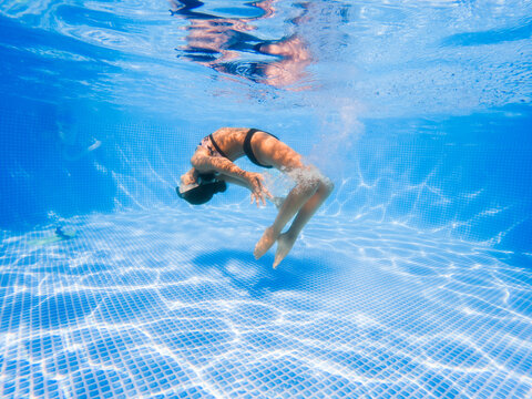Girl floating underwater in a crystal clear pool. 