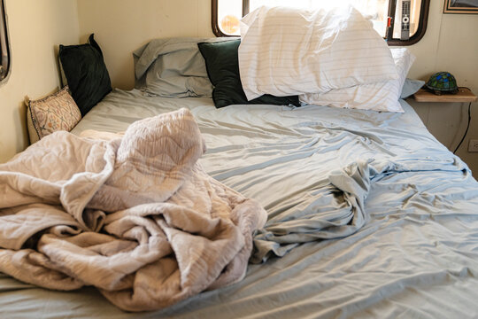 Rustic bedroom interior with tossed sheets and messy pillows.