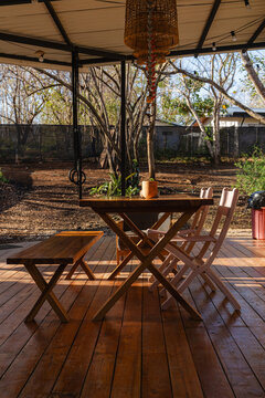 Wooden dining table on an outdoor deck under bright sunlight.