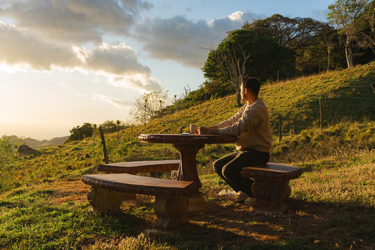 Man enjoying sunset view with coffee at hilltop