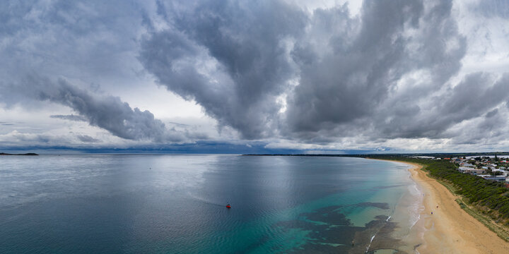 Rain falling from dramatic storm clouds over a calm ocean bay