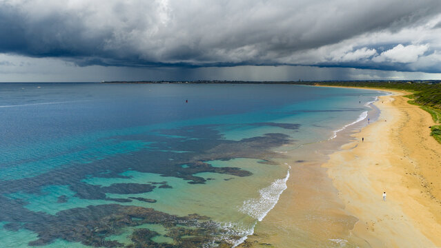 Rain falling from dramatic storm clouds over a calm ocean bay