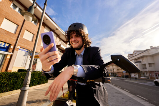 Young man commuting on electric scooter using smartphone