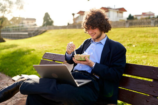 Man eating lunch while working remotely in park