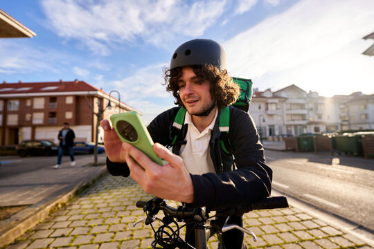 Food delivery rider checking smartphone on city street
