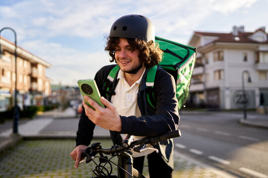 Food delivery rider checking smartphone on bicycle