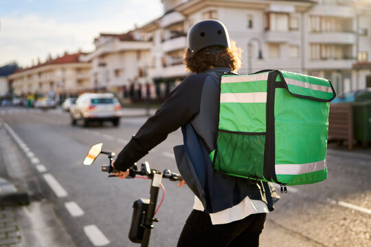 Food delivery courier riding electric scooter in city