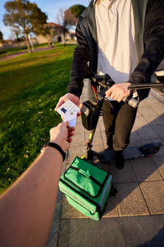 Food delivery rider receiving contactless payment outdoors