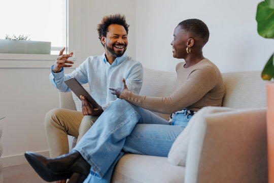 Colleagues enjoying joyful conversation with digital tablet