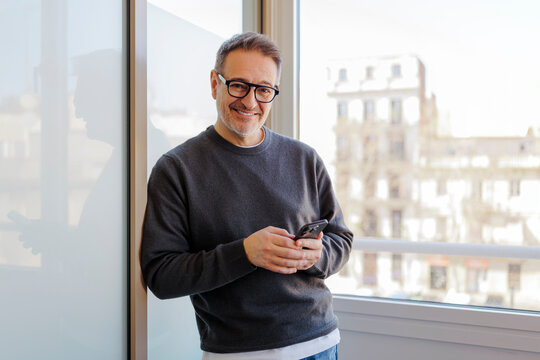 Mature man smiling using cellphone with natural light