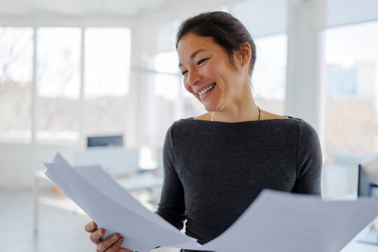 Businesswoman smiling reviewing important documents in office
