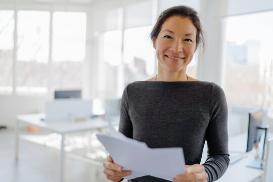 Businesswoman holding documents in modern office