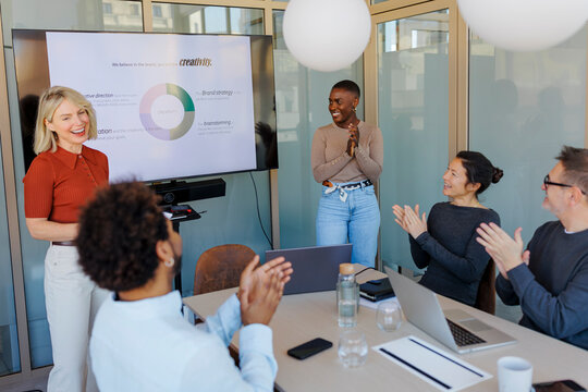 Business colleagues applauding successful project at office
