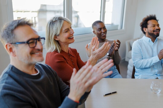 Diverse group applauding success at business meeting