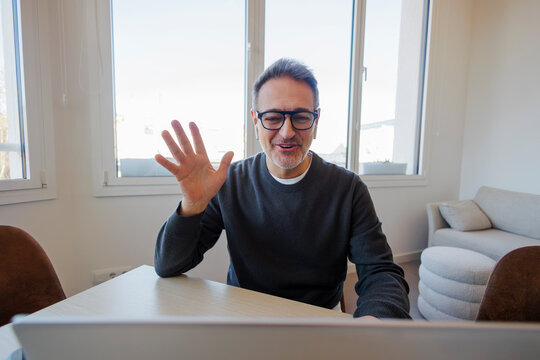Mature man waving during a remote video call