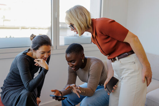 Diverse group of women sharing content on a smartphone during break