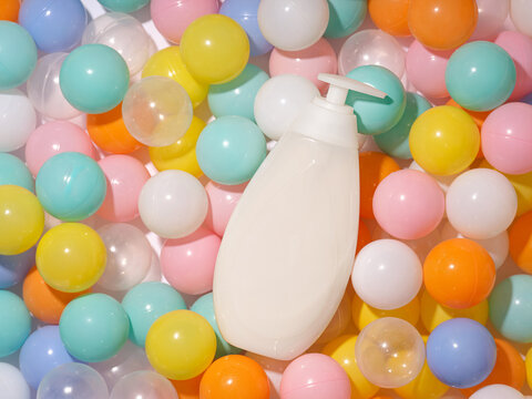 White dispenser bottle with pump surrounded by colorful plastic balls