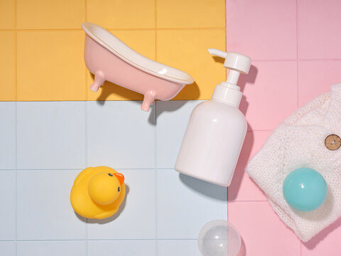 Cute baby bath time essentials arranged on colorful pastel tiles