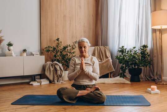 Focused senior woman enjoy yoga exercises practice in calm studio

