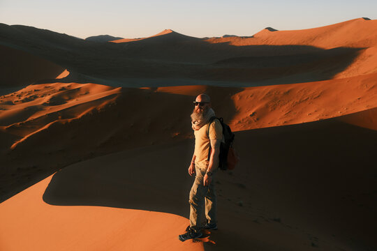 Man standing on red sand dune in Namib Desert, Namibia
