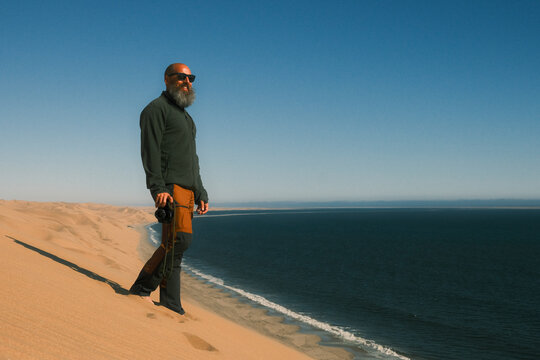 Man standing on red sand dune in Walvis Bay, Namibia
