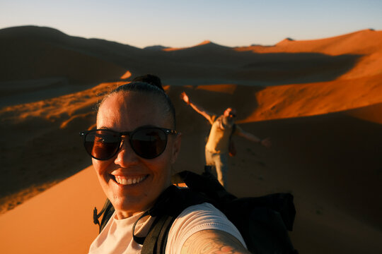 couple take a selfie standing on red sand dune in Namib Desert
