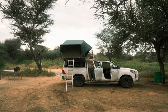 Man setting up rooftop tent on 4x4 vehicle in Namibia
