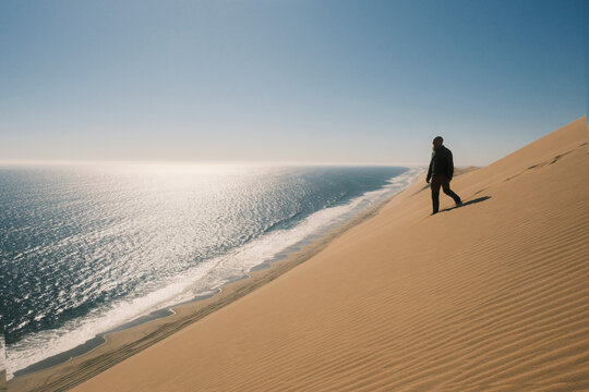 Man standing on red sand dune in Walvis Bay, Namibia
