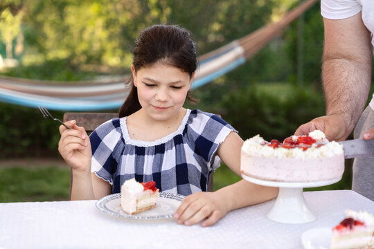Birthday girl tasting her cake her father served on a plate.