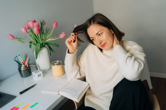 Woman Thinking While Taking Notes at Desk