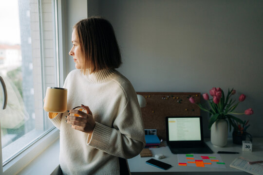 Woman Looking Out Window with Coffee Mug