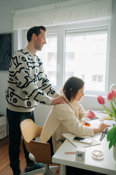 Man Supporting Woman During Remote Work