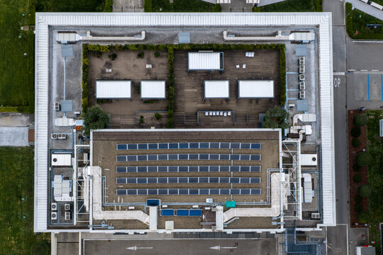 Aerial view of a modern building rooftop featuring solar panels, air conditioning units, and a landscaped terrace with greenery Reggello, Tuscany, Italy.