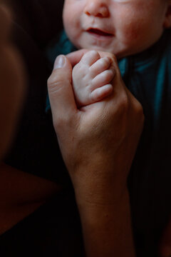 Parent holding newborn baby's hand in tender close-up moment