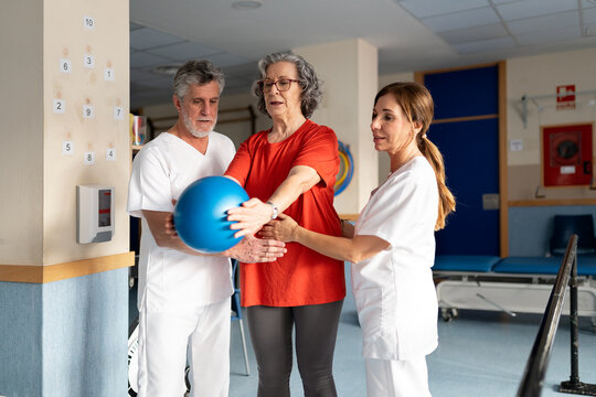 Physiotherapist assisting senior woman with rehabilitation exercise