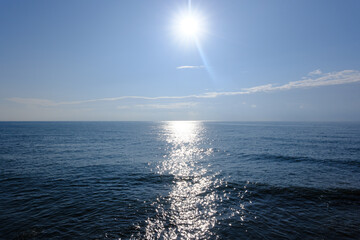 Naklejka premium Sunlight glints on deep blue ocean waters. Rippling surface shimmers with bright sparkles. Calm sea creates peaceful visual. Ideal for nature or relaxation themes. Use in travel or wellness contexts