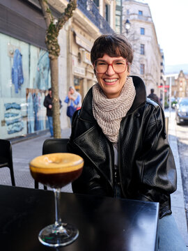 Woman smiling enjoying a coffee cocktail happy in city