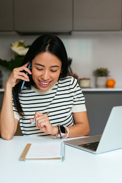 Young Businesswoman Talking on Smartphone While Working from Home
