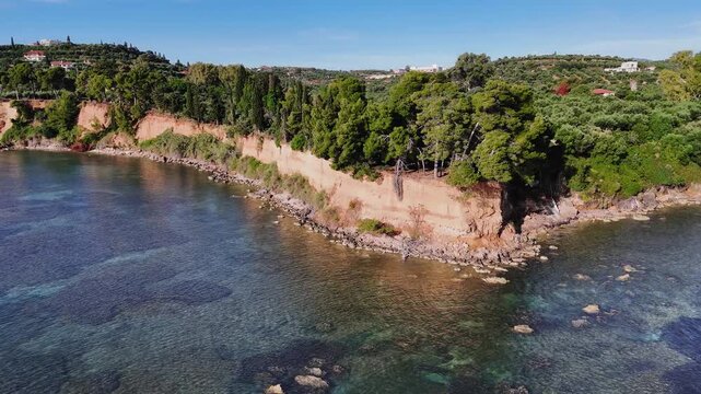 Aerial view of rocky Mediterranean coastline with turquoise water, forested cliffs and coastal houses, calm sea and natural landscape, scenic seaside environment
