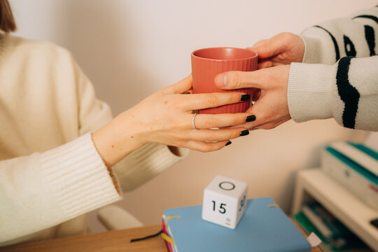 Close Up of Hands Passing Coffee Mug