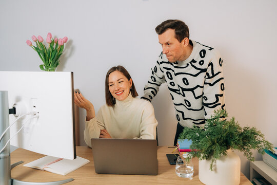 Couple collaborating at desk with laptop and monitor