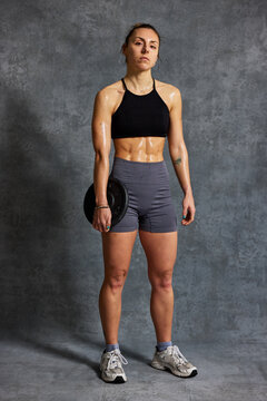 Woman lifts weight in sporty outfit during indoor workout sessio