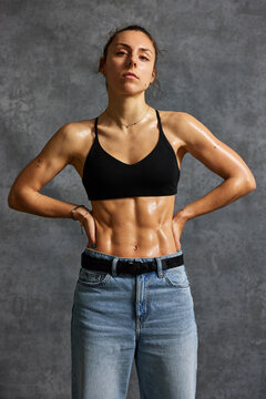 Fitness model poses with toned body in studio setting