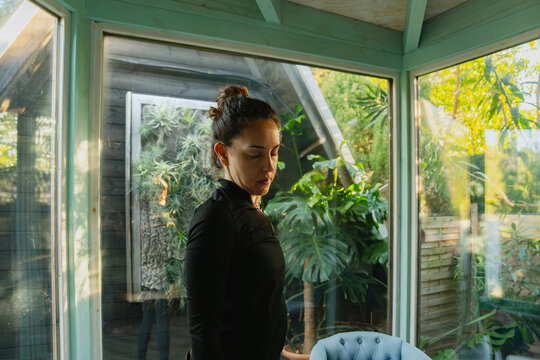 Woman practicing mindfulness yoga in greenhouse with plants