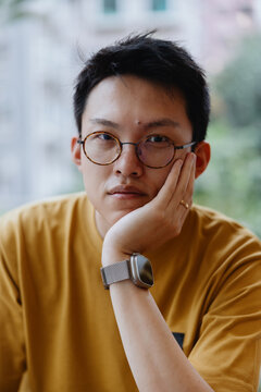 Portrait of Young Man Wearing Glasses Resting Face on Hand