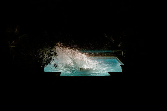 Kids jumping and playing in a pool at night on their vacation. 